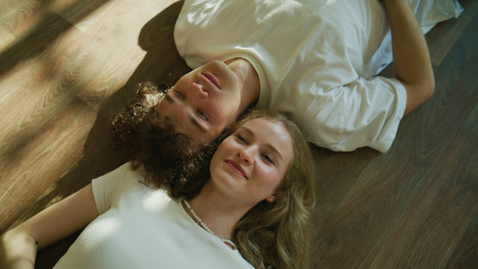 Two people relaxing on a wooden floor in natural light