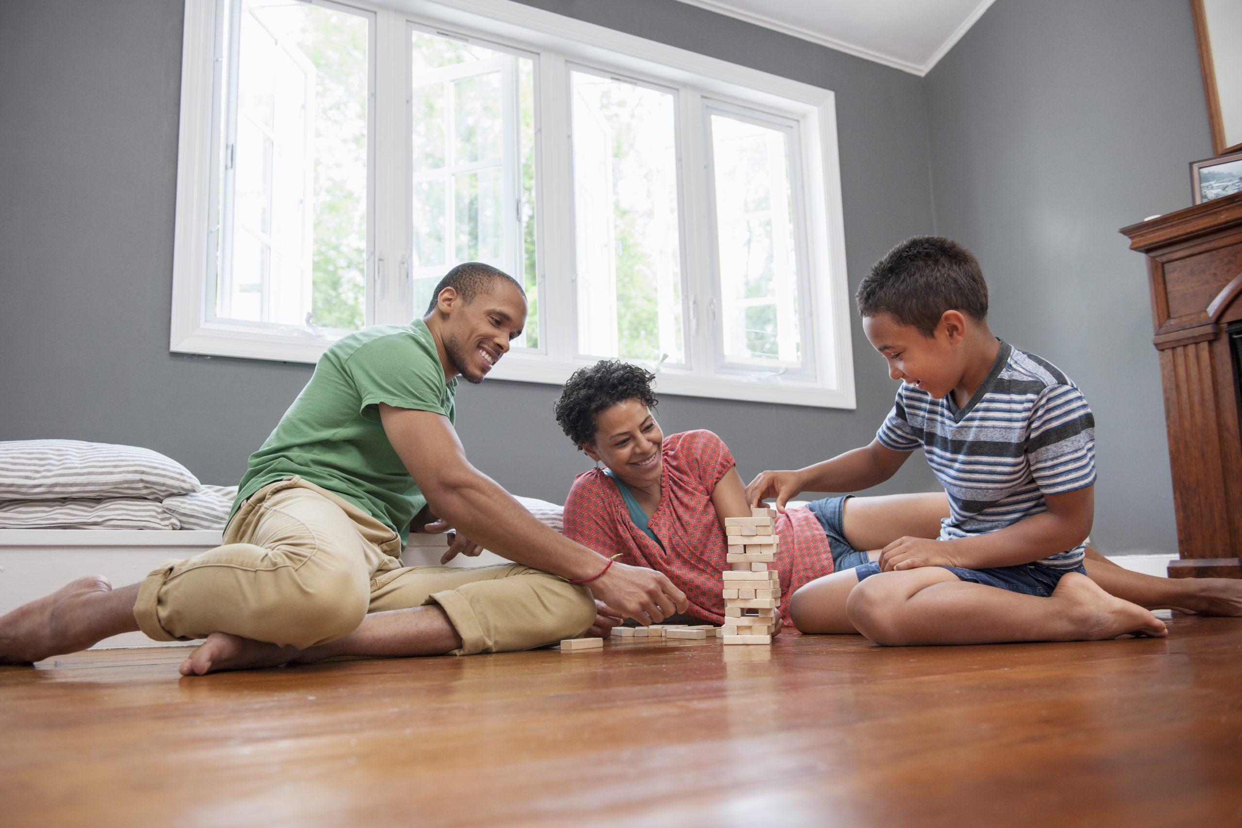 Family sitting on a warm hardwood floor playing a tabletop game at home