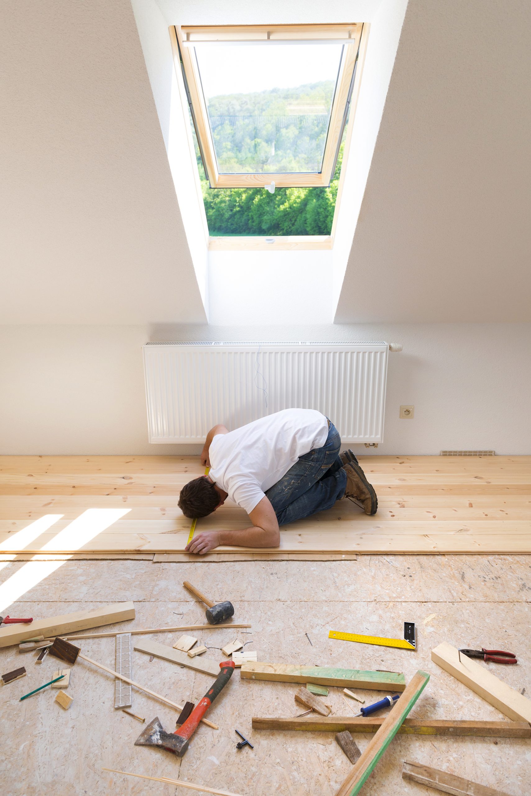 Floor installer measuring and fitting hardwood planks on a subfloor